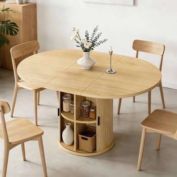 Oval woody  eating  array  with halfway  retention  shelves, decoratively arranged with a vase and candle, surrounded by 4  matching chairs