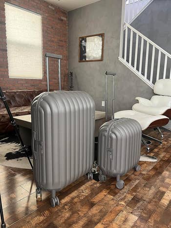 Two suitcases side by side in a home interior with a stairway in the background