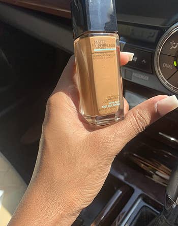 reviewer holding up the bottle of foundation and showing how the product they applied to their hand matches their natural skin tone