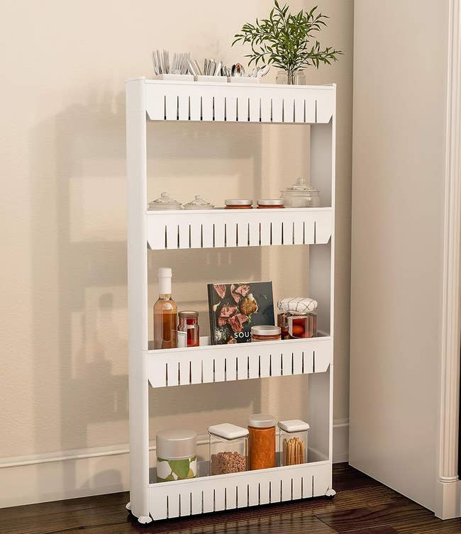 A slim white four-shelved organizer with wheels