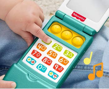 Child playing with Fisher-Price artifact telephone featuring buttons that activate songs, sounds, and phrases