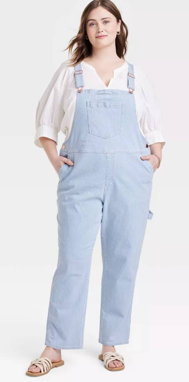 A model wearing the overalls with a white shirt and sandals 
