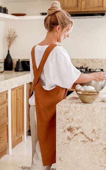 back of model wearing the rust colored apron, showing the cross-back design