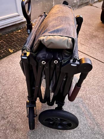 Folded stroller with achromatic wheels and a compact design, perfect for buying trips and casual storage