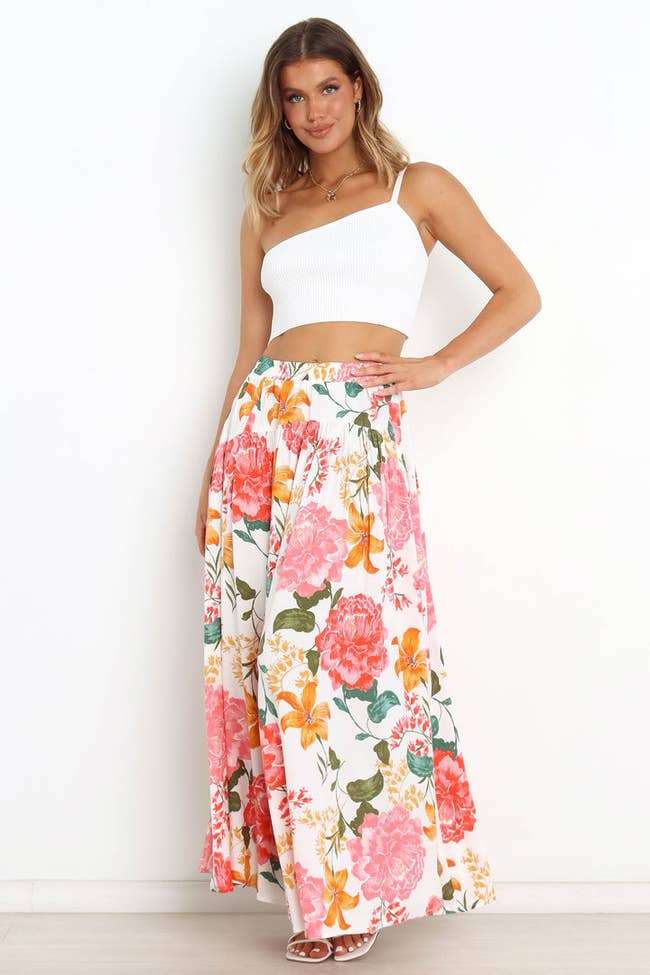 model in white skirt with orange, green, and pink large floral print