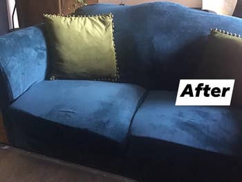 same couch covered with a dark blue velvet slip cover and green accent pillows