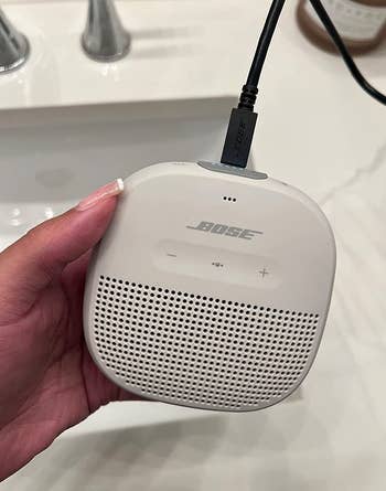 reviewer charging a white bose speaker