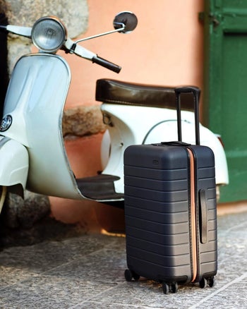 Instagram photo of black Away suitcase near a scooter