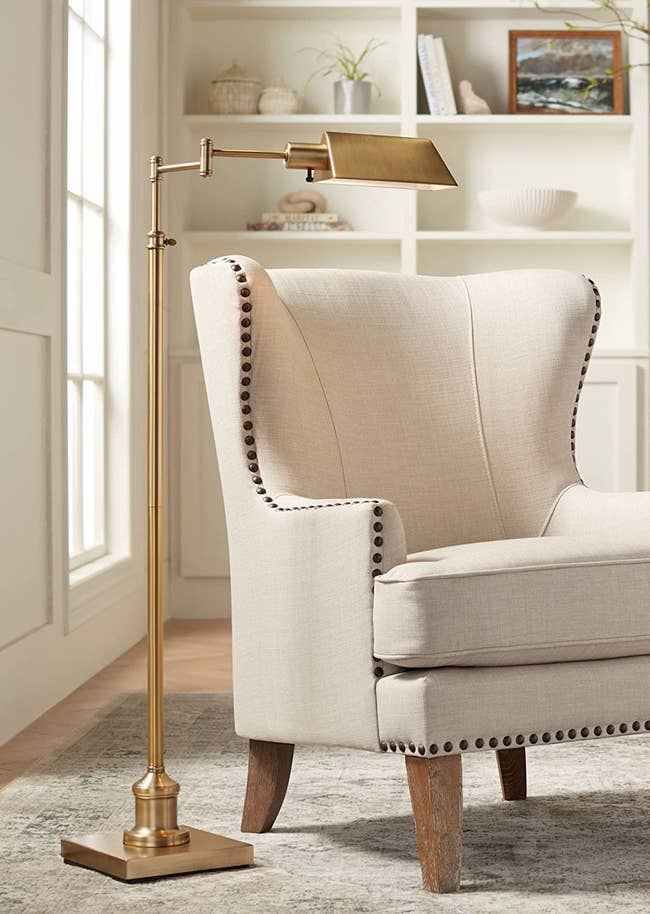 the gold floor lamp next to a cream arm chair