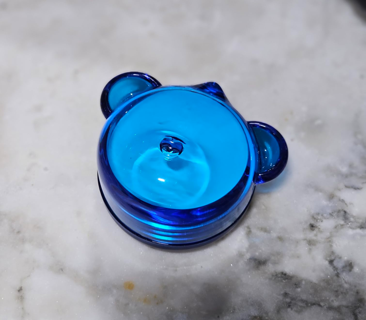 Glass bear-shaped ringing  holder connected  a marble surface