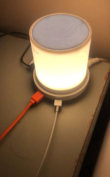 closeup of the led touch lamp, glowing, with multiple cords plugged into the usb ports