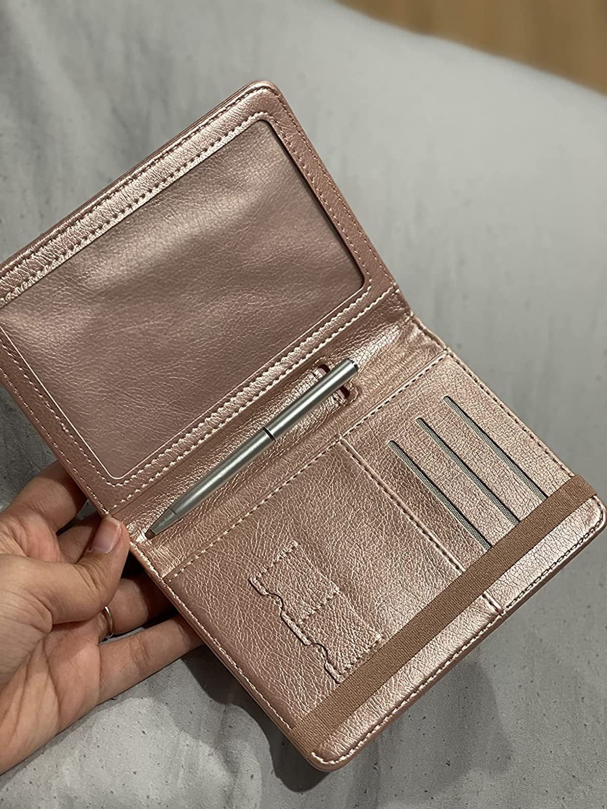 Reviewer photo of the rose gold colored passport and vaccine holder with a pen in the middle