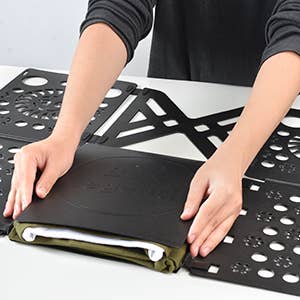 Person utilizing a folding committee  to neatly fold a garment  connected  a table