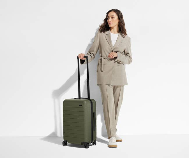 model posing with olive green suitcase