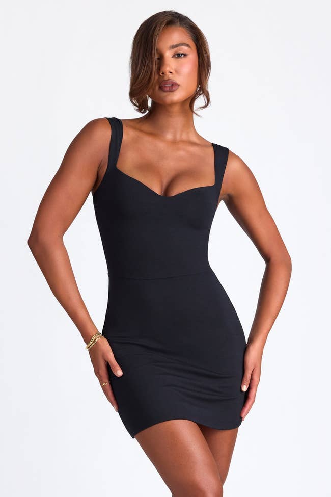 model wearing black mini dress with sweetheart neckline