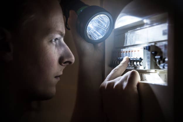 Person using a flashlight to examine electric circuit breakers