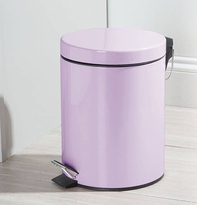 a pale purple trash can wih a lid 