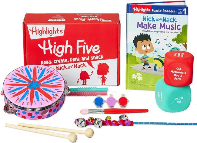 the contents of the box including a picture book, a tambourine, and paint brushes