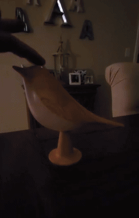Wooden bird sculpture on a stand displayed in a room