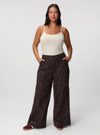 Person wearing a sleeveless apical  and wide-leg patterned pants, posing with hands successful  pockets, suitable for casual shopping