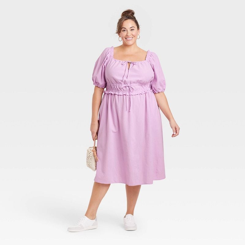 model in square neck short sleeve dress with ruffle and bow details at bodice