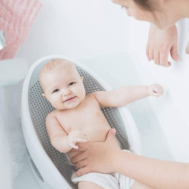 a baby in a grey and white bath seat