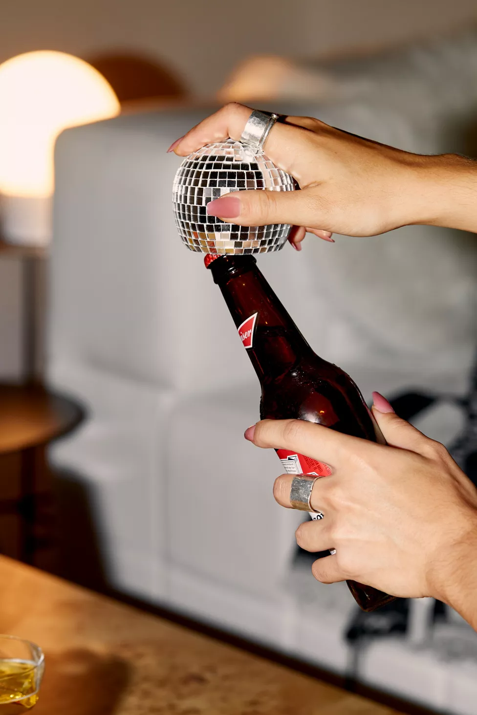 model opening a beer bottle with a small disco ball opener 