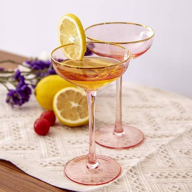 Two elegant stem glasses with a slice of lemon on one, on a lace tablecloth for a chic decor piece