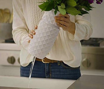 A model twisting open a white flower vase at the base 