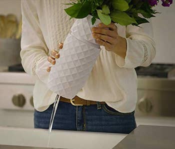 A model twisting open a white flower vase at the base 