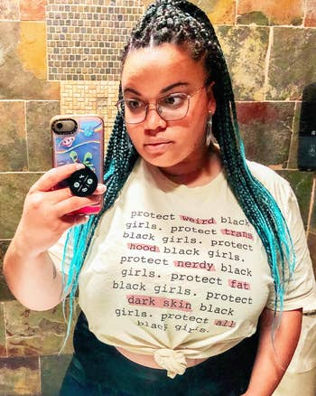 Person with braided hair takes selfie wearing T-shirt with text supporting protection of various groups of black girls