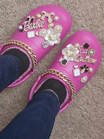 Pink clogs adorned with various decorative charms, pearls, and