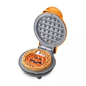 Mini waffle shaper  with an unfastened  lid, showing a waffle with a Halloween pumpkin plan  connected  the top