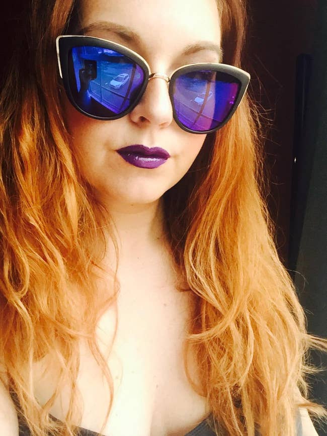 reviewer in black cat eye sunnies with gold trim and tinted lenses