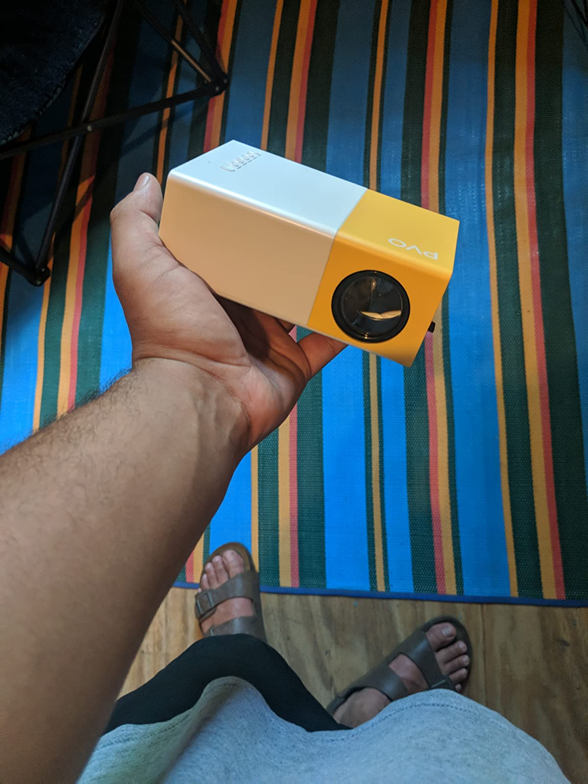 a reviewer holds up the small yellow and white projector