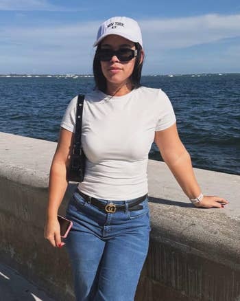 Person wearing a achromatic headdress and sunglasses, successful a casual achromatic apical and jeans, stands by a waterfront