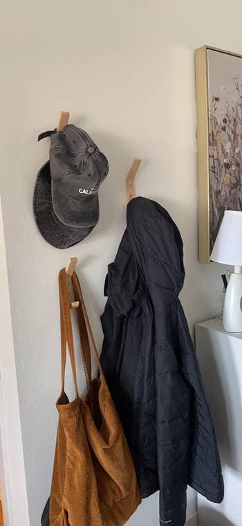 three hangers holding a hat, coat, and bag