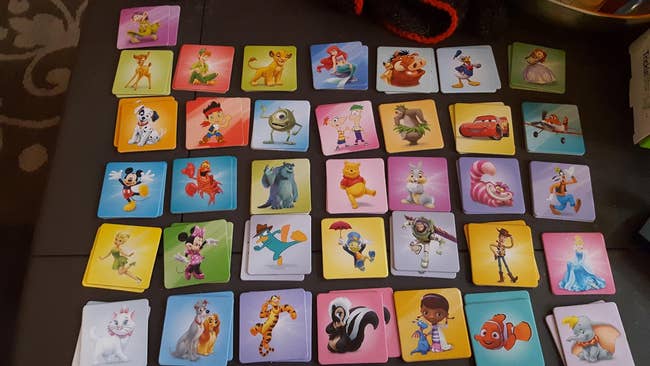 Board game with Disney character tiles, including Simba, Ariel, Mickey Mouse, and Woody, arranged on a table for a children&rsquo;s activity