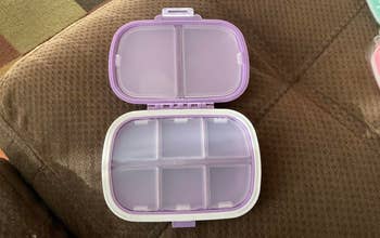 Open multi-compartment lunchbox with a purple lid, connected a brownish couch