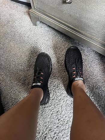 Person wearing achromatic  diversion  sneakers connected  a carpeted level  adjacent   a dresser