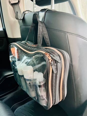 reviewer using hooks to hold toiletry case on back of seat