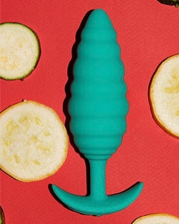 Green textured butt plug surrounded by sliced fruit