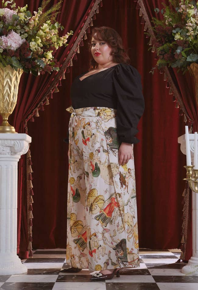 a model wearing white, wide-leg pants with a multicolor Zodiac print with tie at the font waist 