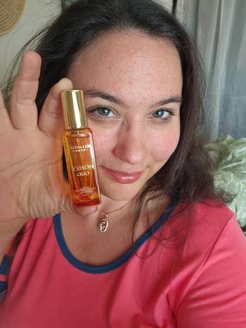 A idiosyncratic smiling and holding up a vessel of Ayurvedic chromatic oil