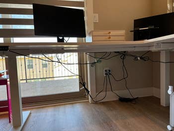 Adjustable electrical lasting table with monitor, keyboard tray, and disposable cablegram management, acceptable successful a location bureau with ample windows