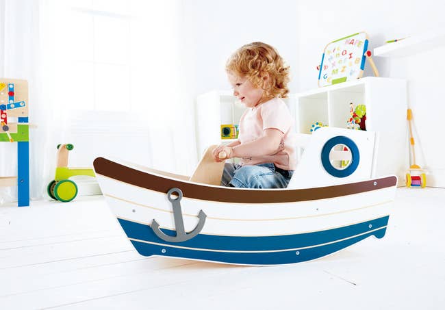 a child in a boat toy that rocks back and forth