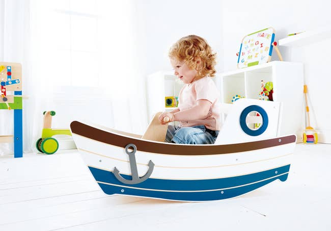 a child in a boat toy that rocks back and forth