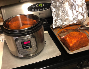 a reviewer photo of the instant pot next to meat that was cooked in the instant pot
