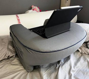 Laptop on a cushioned lap desk on a bed