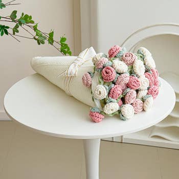 Bouquet of knitted roses with a decorative ribbon on a round table, suitable for home decor or as a unique gift